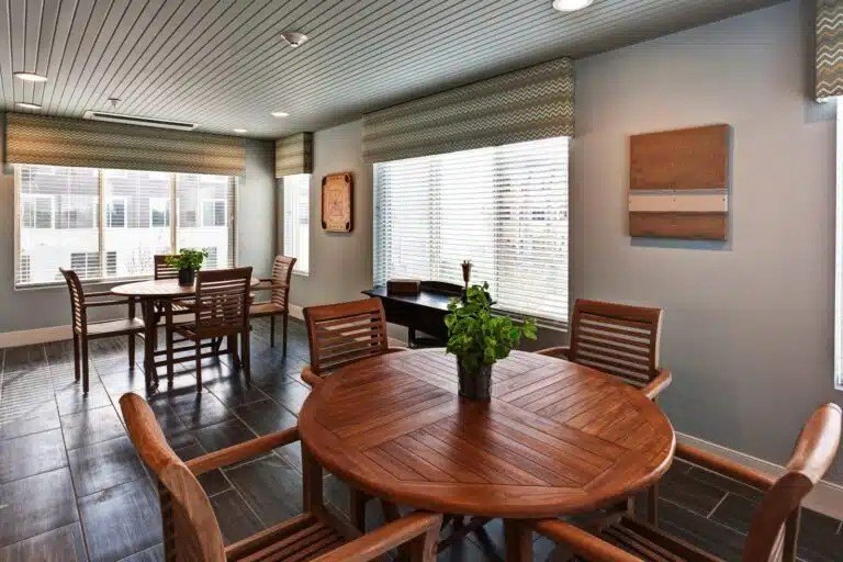 A wooden table with chairs around it in a room with a window  at The Piper, Kansas City, KS.